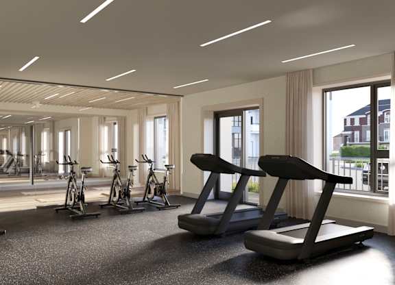 A spacious gym with treadmills, exercise bikes, and a view of the city at Roxy Apartments, Hamilton, ON