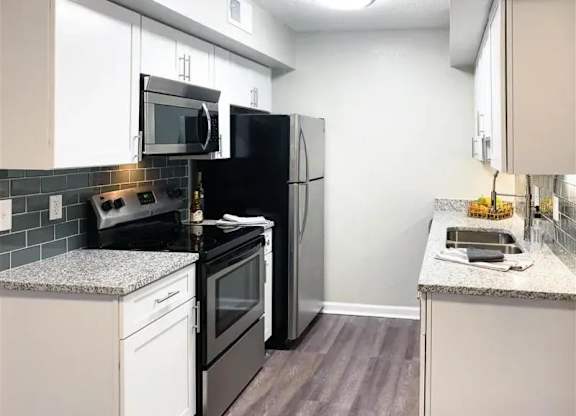 A kitchen with black appliances and white cabinets. at Latitude at Riverchase, Hoover, AL, 35216