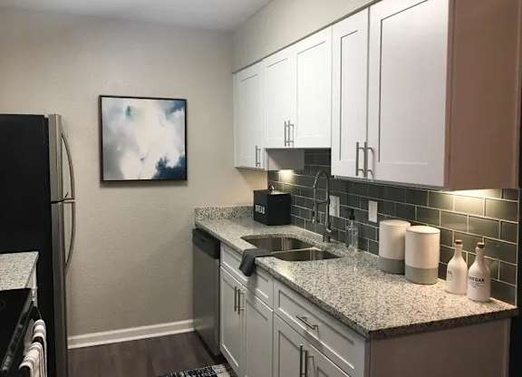 A kitchen with a black refrigerator and white cabinets. at Latitude at Riverchase, Hoover, AL, 35216