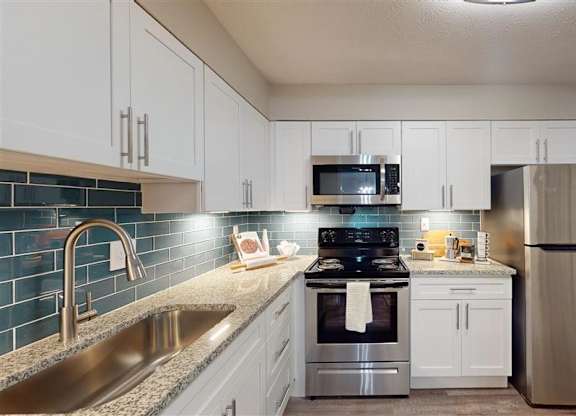 A kitchen with a stainless steel refrigerator, sink, and stove. at Vinings RiverVue, Georgia, 30339