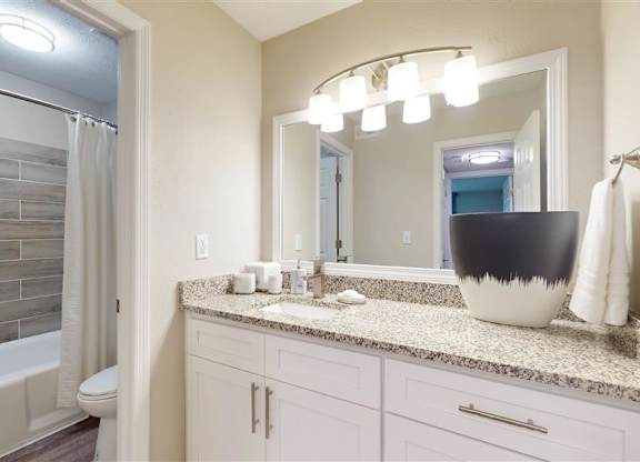 A bathroom with a marble countertop and a large mirror. at Vinings RiverVue, Georgia