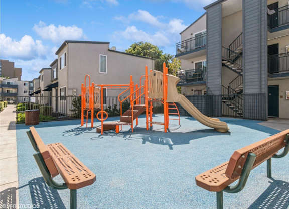 A playground with a slide and swings in front of a building at Oak Center Apartments, Oakland, California