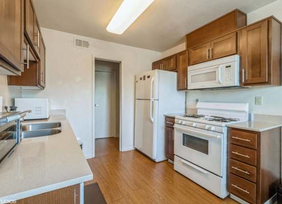 A kitchen with white appliances and wooden cabinets at Oak Center Apartments, Oakland