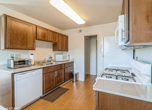 A kitchen with a white stove top oven and wooden cabinets at Oak Center Apartments, Oakland, California