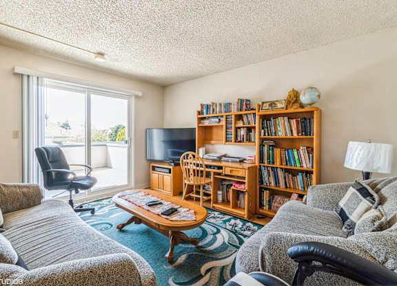 A living room with a grey couch, a wooden bookshelf, and a coffee table at Oak Center Apartments, Oakland, 94607