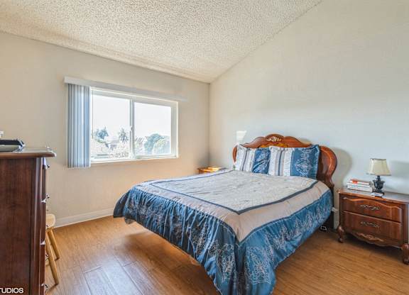 A bedroom with a bed, nightstand, and window at Oak Center Apartments, Oakland, 94607