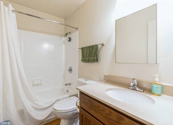 A white bathroom with a toilet, sink, and shower at Oak Center Apartments, Oakland, CA
