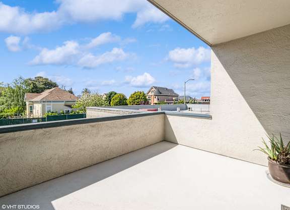 A balcony with a potted plant on the edge overlooks a residential area at Oak Center Apartments, Oakland, CA, 94607