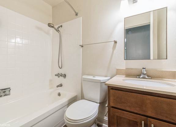 A white bathroom with a toilet, sink, and tub at Oak Center Apartments, California