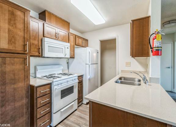 A kitchen with white appliances and wooden cabinets at Oak Center Apartments, Oakland, 94607