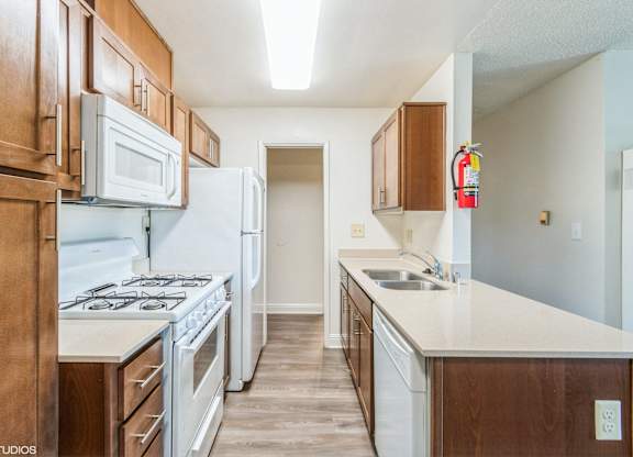 A kitchen with white appliances and wooden cabinets at Oak Center Apartments, Oakland, CA