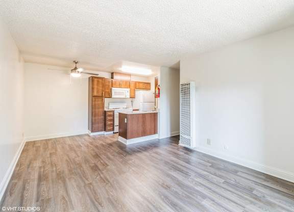 A spacious room with wooden flooring and a kitchenette in the background at Oak Center Apartments, California, 94607