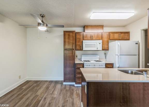 A kitchen with wooden cabinets and a white fridge at Oak Center Apartments, California