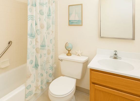 A bathroom with a toilet, sink, and shower curtain at Mohican Apartments, New London, CT, 06320