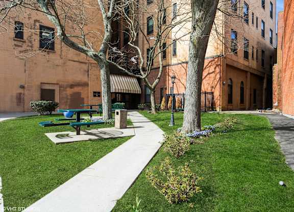 A park with a bench and a tree in front of a brick building at Mohican Apartments, New London, 06320