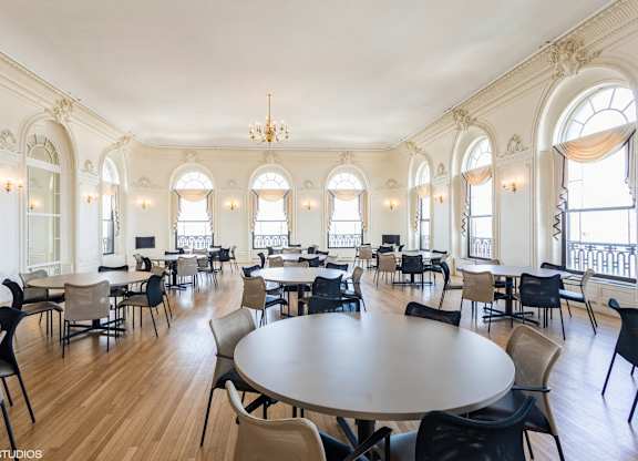 A large room with tables and chairs and a balcony with a railing at Mohican Apartments, New London, CT, 06320