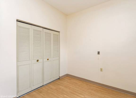Closed white doors with brass knobs in a room with wooden floor and white walls at Mohican Apartments, Connecticut, 06320