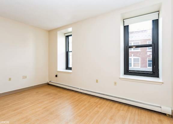 Empty room with a window and wooden floor at Mohican Apartments, New London
