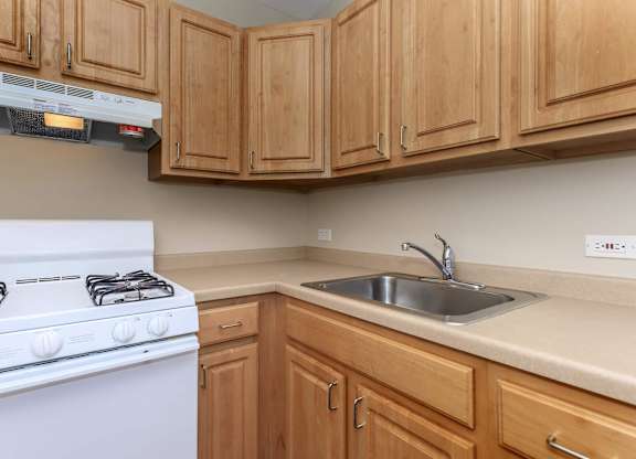 A white gas stove is in a kitchen with wooden cabinets at Sheridan Park, Chicago, IL