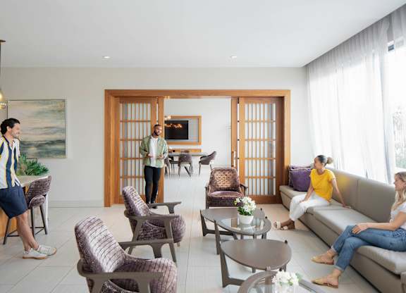 A man in a striped shirt is standing in a living room with two women sitting on a couch. at Palma, Florida