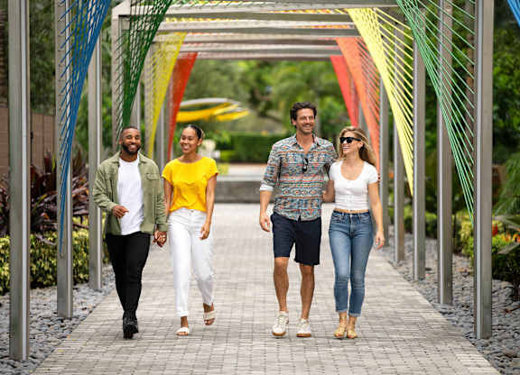 Four people walking on a bridge with a metal structure. at Palma, Doral, 33166