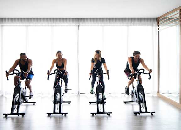 Four people are riding stationary bikes in a row. at Palma, Doral, 33166