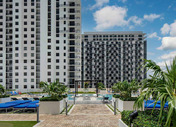 A modern building with a pool in front. at Palma, Doral, FL, 33166