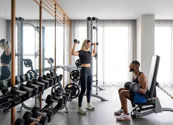 A man and woman are working out in a gym with various exercise equipment. at Palma, Doral, 33166