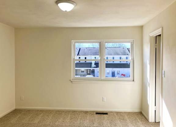 A room with a window and a carpeted floor.