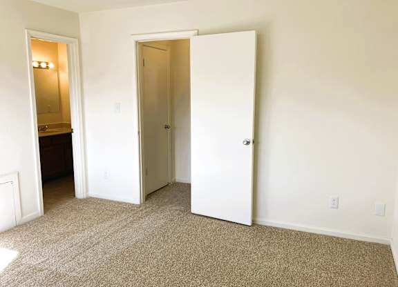 A room with a carpeted floor and two white doors.