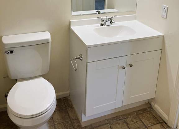 A white toilet sits next to a white sink in a bathroom.