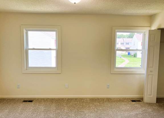A room with a window and a door leading to a view of a street.