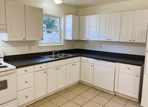A kitchen with white cabinets and black countertops.