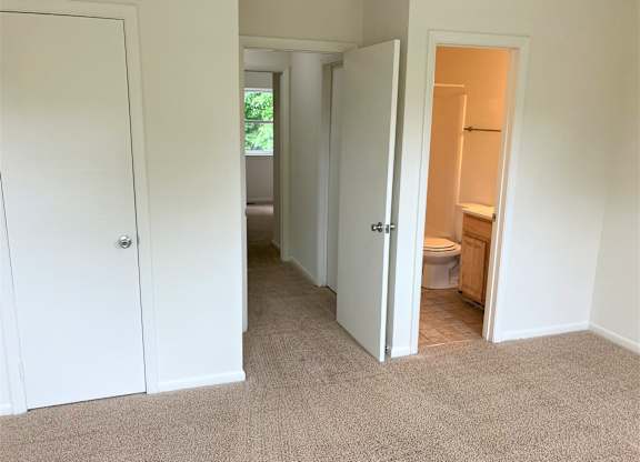 A white door is open to a bathroom with a toilet and sink.