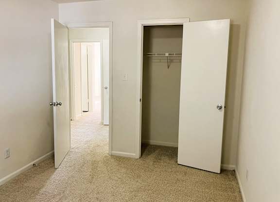 A room with a carpeted floor and two white doors.