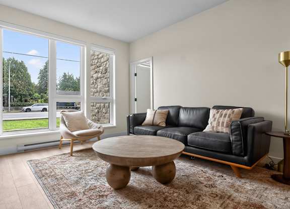A living room with a black couch and a wooden coffee table.