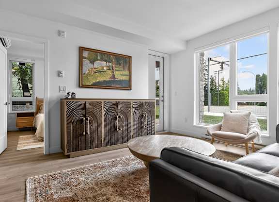 A living room with a grey couch and a brown rug.