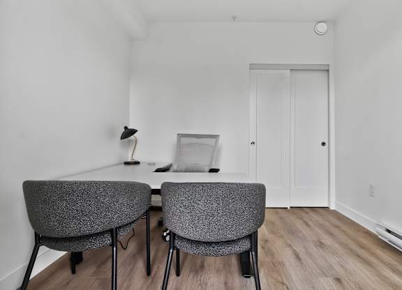 Two grey chairs are placed in a room with a white wall and a door.