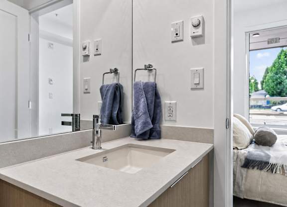A bathroom with a sink, mirror, and towel rack.