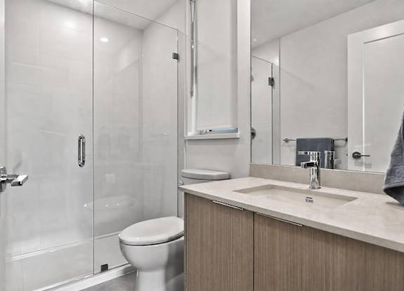 A modern bathroom with a toilet, sink, and shower.