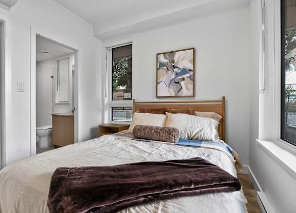 A bedroom with a large bed and a painting on the wall.