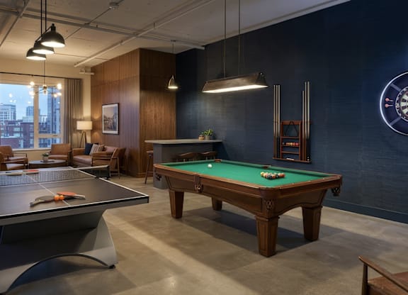 A pool table in a room with a dartboard on the wall.