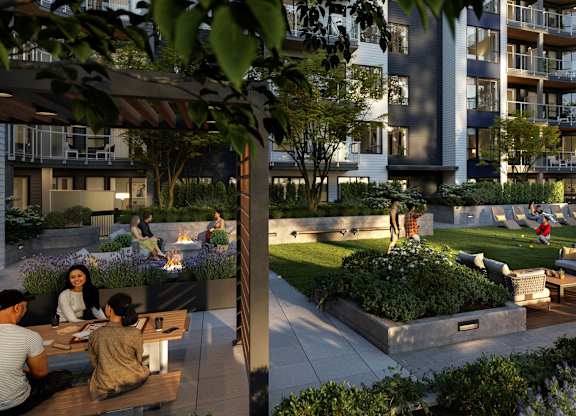 A group of people are sitting around a fire pit in a courtyard.