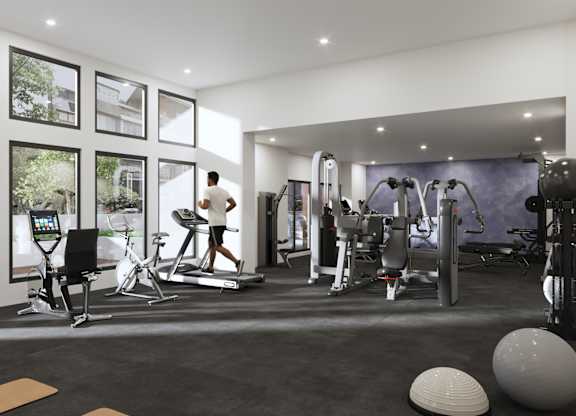 A man is working out on a treadmill in a spacious gym with various exercise equipment.
