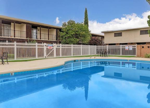 A swimming pool in front of a building with a fence around it.