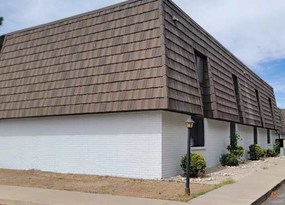 A white house with a brown roof and a black lamp post.