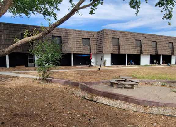 A building with a brown roof and a tree in front of it.