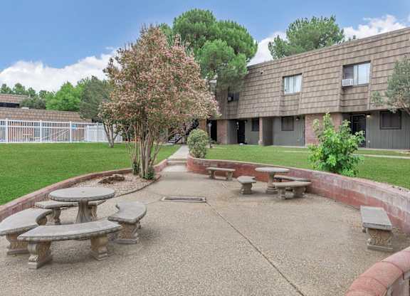 A courtyard with a tree and benches in front of a building.