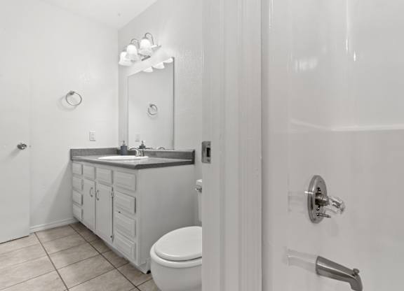 A white bathroom with a toilet, sink, and mirror.