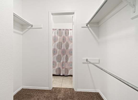 A white hallway with a brown carpet and a doorway leading to a bathroom.